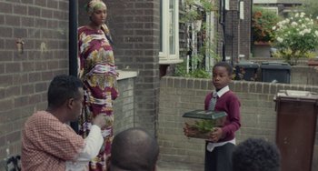 Movie still from “Rocks” (2019), directed by Sarah Gavron – A woman and a boy are holding a box; Wide shot, Over the shoulder angle