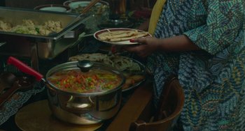 Movie still from “Rocks” (2019), directed by Sarah Gavron – A person holding a plate of food in front of a bowl of food; Extreme Close Up shot, High angle