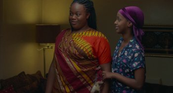 Movie still from “Rocks” (2019), directed by Sarah Gavron – Two young women standing next to each other in a room; Medium shot, Over the shoulder angle