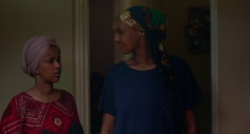 Movie still from “Rocks” (2019), directed by Sarah Gavron – A woman with a head scarf standing next to another woman; Medium shot, Over the shoulder angle