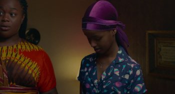 Movie still from “Rocks” (2019), directed by Sarah Gavron – A woman wearing a purple headscarf and a blue shirt; Medium shot, Over the shoulder angle