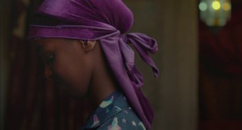 Movie still from “Rocks” (2019), directed by Sarah Gavron – A woman wearing a purple head scarf and a blue shirt; Close Up shot, Over the shoulder angle