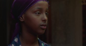 Movie still from “Rocks” (2019), directed by Sarah Gavron – A person wearing a purple hat; Close Up shot, Over the shoulder angle