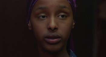 Movie still from “Rocks” (2019), directed by Sarah Gavron – A person wearing a purple head scarf; Close Up shot, Over the shoulder angle