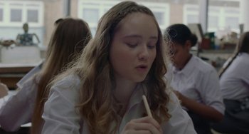 Movie still from “Rocks” (2019), directed by Sarah Gavron – A young girl is holding a pencil in her hand; Close Up shot, Over the shoulder angle