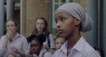 Movie still from “Rocks” (2019), directed by Sarah Gavron – A group of young people sitting in a row; Close Up shot, Over the shoulder angle