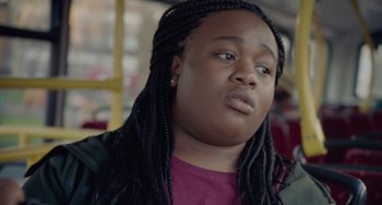 Movie still from “Rocks” (2019), directed by Sarah Gavron – A woman with long braids sitting on a bus; Close Up shot, Over the shoulder angle