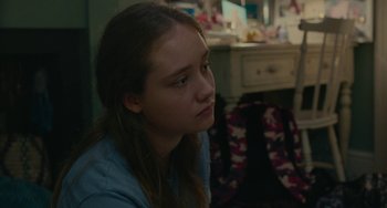 Movie still from “Rocks” (2019), directed by Sarah Gavron – A young girl sitting in a room looking off into the distance; Close Up shot, Over the shoulder angle