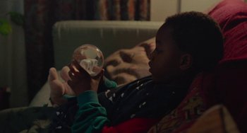 Movie still from “Rocks” (2019), directed by Sarah Gavron – A young boy holding a glass ball in his hands; Close Up shot, High angle