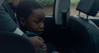 Movie still from “Rocks” (2019), directed by Sarah Gavron – A young boy sitting in the back seat of a car; Close Up shot, Over the shoulder angle
