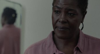 Movie still from “Rocks” (2019), directed by Sarah Gavron – An older woman wearing a pink shirt looking to her left; Close Up shot, Over the shoulder angle