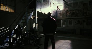 Movie still from “Rocky Balboa” (2006), directed by Sylvester Stallone – A man standing in the dark in front of a building; Wide shot, Low angle