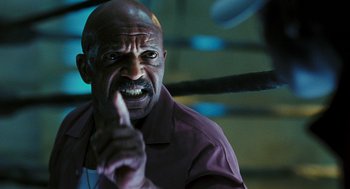 Movie still from “Rocky Balboa” (2006), directed by Sylvester Stallone – A man with a beard and a shirt is pointing his finger at the camera; Close Up shot, Low angle