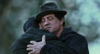 Movie still from “Rocky Balboa” (2006), directed by Sylvester Stallone – Sylvester stallone hugging a man in a black hat; Close Up shot, Over the shoulder angle