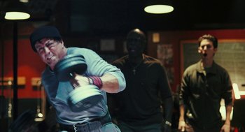 Movie still from “Rocky Balboa” (2006), directed by Sylvester Stallone – A man swinging a baseball bat at a game; Medium shot, Over the shoulder angle