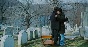 Movie still from “Rocky Balboa” (2006), directed by Sylvester Stallone – Two men hug in front of a grave in a cemetery; Wide shot, Over the shoulder angle