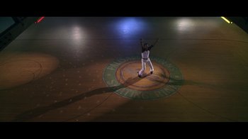 Movie still from “Roll Bounce” (2005), directed by Malcolm D. Lee – A man in white pants and a white shirt is on a wooden floor; Extreme Wide shot, High angle