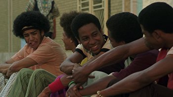 Movie still from “Roll Bounce” (2005), directed by Malcolm D. Lee – A group of young men sitting next to each other; Medium shot, Low angle