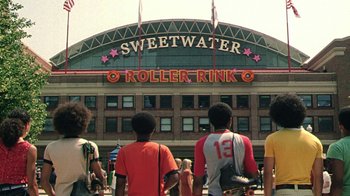 Movie still from “Roll Bounce” (2005), directed by Malcolm D. Lee – A group of people standing in front of a roller rink; Wide shot, Low angle