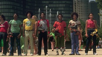Movie still from “Roll Bounce” (2005), directed by Malcolm D. Lee – A group of young men standing next to each other on a sidewalk; Wide shot, Low angle