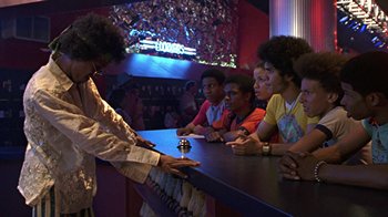 Movie still from “Roll Bounce” (2005), directed by Malcolm D. Lee – A group of young people sitting around a bar; Medium shot, Over the shoulder angle