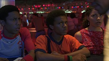 Movie still from “Roll Bounce” (2005), directed by Malcolm D. Lee – A young man sitting in front of an audience at an event; Close Up shot, Low angle