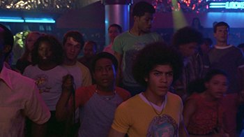 Movie still from “Roll Bounce” (2005), directed by Malcolm D. Lee – A group of young men standing in front of a microphone; Medium shot, Low angle