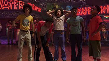 Movie still from “Roll Bounce” (2005), directed by Malcolm D. Lee – A group of young men standing on a dance floor in front of neon signs; Medium shot, Low angle