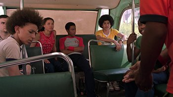 Movie still from “Roll Bounce” (2005), directed by Malcolm D. Lee – A group of people sitting on a bus; Medium shot, Over the shoulder angle