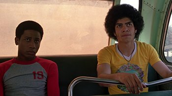 Movie still from “Roll Bounce” (2005), directed by Malcolm D. Lee – Two young men sitting on a bus looking at the camera; Medium shot, Low angle