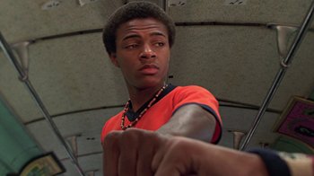 Movie still from “Roll Bounce” (2005), directed by Malcolm D. Lee – A young black man in an orange t - shirt is holding his fist; Close Up shot, Low angle
