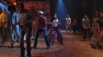 Movie still from “Roll Bounce” (2005), directed by Malcolm D. Lee – A group of young people riding skateboards on a dance floor; Wide shot, Low angle