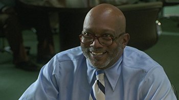 Movie still from “Roll Bounce” (2005), directed by Malcolm D. Lee – An older man wearing a blue shirt and a blue tie; Close Up shot, Low angle