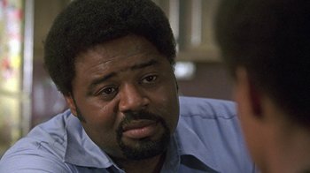 Movie still from “Roll Bounce” (2005), directed by Malcolm D. Lee – A man with a beard is sitting in front of another man; Close Up shot, Over the shoulder angle