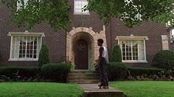 Movie still from “Roll Bounce” (2005), directed by Malcolm D. Lee – A boy standing in front of a brick house; Wide shot, Low angle