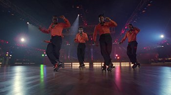 Movie still from “Roll Bounce” (2005), directed by Malcolm D. Lee – A group of men on skateboards performing a dance routine; Wide shot, Low angle