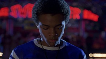 Movie still from “Roll Bounce” (2005), directed by Malcolm D. Lee – A young man with his eyes closed in front of a neon sign; Close Up shot, Low angle