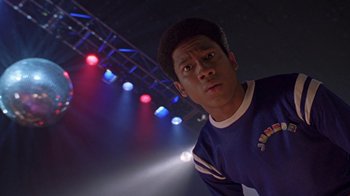 Movie still from “Roll Bounce” (2005), directed by Malcolm D. Lee – A man standing in front of a stage with lights in the background; Close Up shot, Low angle