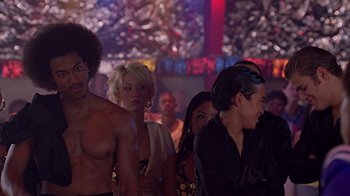 Movie still from “Roll Bounce” (2005), directed by Malcolm D. Lee – A group of people standing around in a room; Medium shot, Over the shoulder angle
