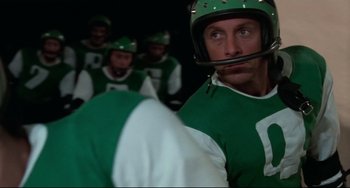 Movie still from “Rollerball” (1975), directed by Norman Jewison – A football player wearing a green jersey; Close Up shot, Low angle