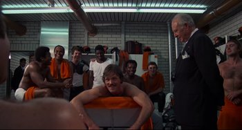 Movie still from “Rollerball” (1975), directed by Norman Jewison – A group of people in a room with a man in a chair; Medium shot, Low angle