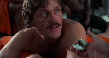 Movie still from “Rollerball” (1975), directed by Norman Jewison – A man with a mustache is looking at the camera; Close Up shot, Low angle