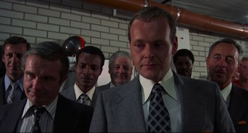 Movie still from “Rollerball” (1975), directed by Norman Jewison – A group of men standing next to each other in a room; Close Up shot, Low angle