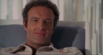 Movie still from “Rollerball” (1975), directed by Norman Jewison – A person sitting on a couch; Close Up shot, Low angle