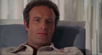 Movie still from “Rollerball” (1975), directed by Norman Jewison – A person sitting in a chair; Close Up shot, Low angle