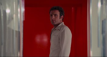 Movie still from “Rollerball” (1975), directed by Norman Jewison – A man standing in front of a red wall; Medium shot, Low angle