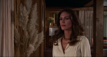 Movie still from “Rollerball” (1975), directed by Norman Jewison – A woman in a white shirt standing next to a plant; Medium shot, Low angle