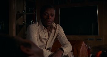 Movie still from “Rollerball” (1975), directed by Norman Jewison – A man sitting on top of a brown leather couch; Close Up shot, Low angle