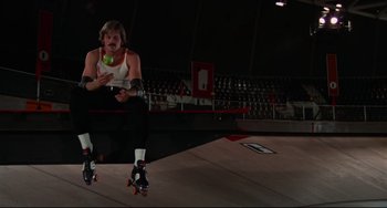 Movie still from “Rollerball” (1975), directed by Norman Jewison – A person on roller blades holding a tennis ball; Wide shot, Low angle