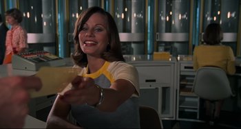 Movie still from “Rollerball” (1975), directed by Norman Jewison – A woman sitting at a table in front of a kitchen; Medium shot, Low angle